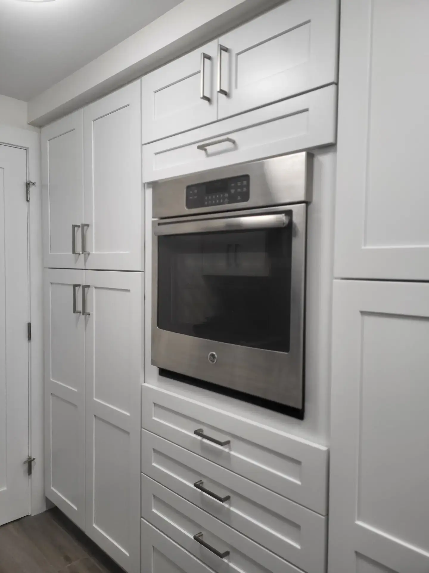 Wall of white shaker cabinet doors and drawer fronts around a wall oven