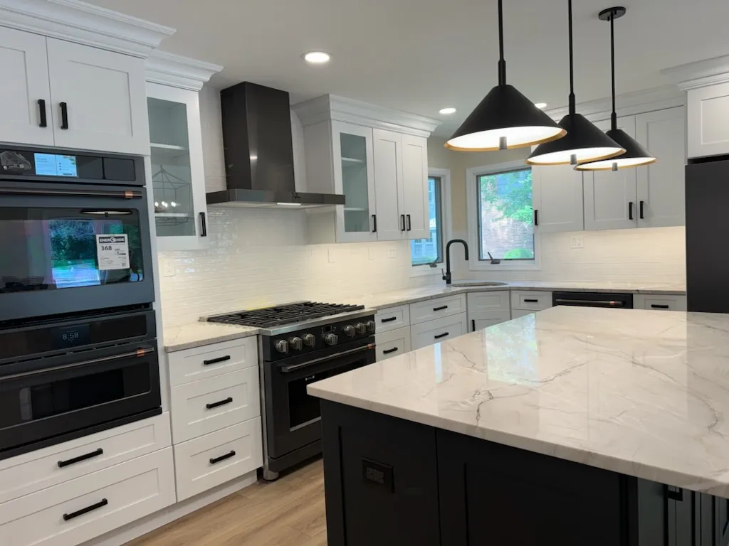 White kitchen with black appliances and a dark island