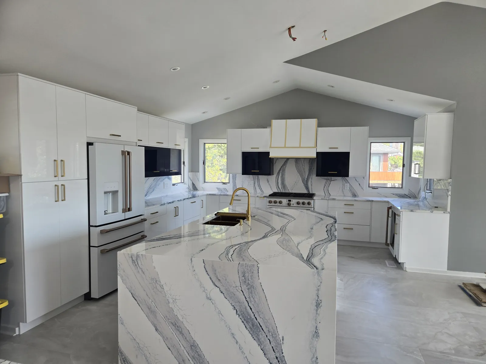 Vaulted white kitchen with a dramatic stone waterfall island