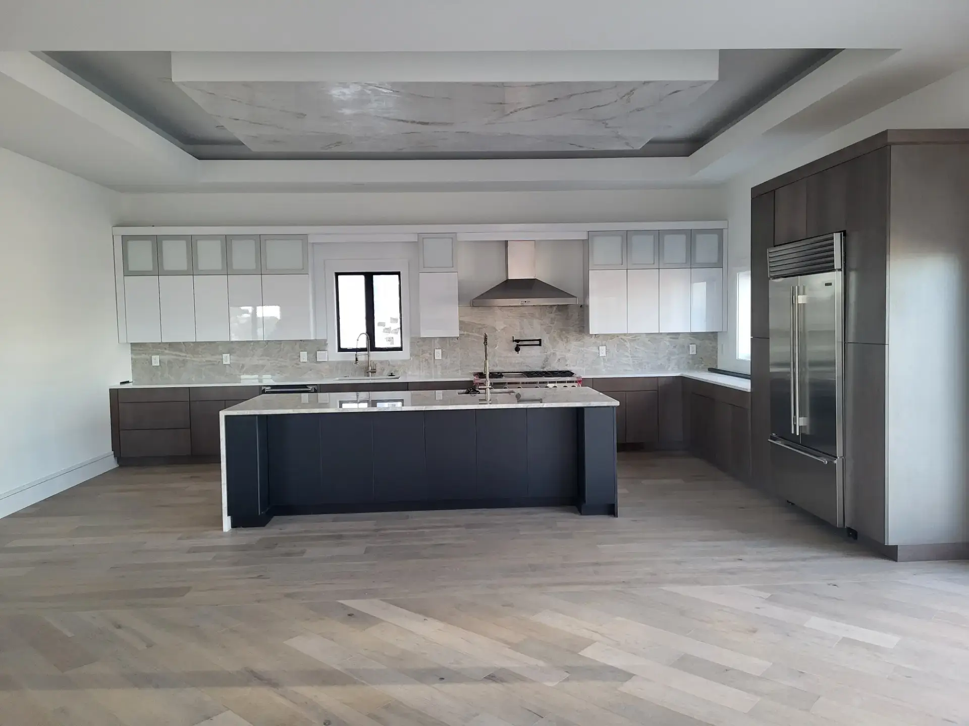 Newly finished kitchen with a dark island and white perimeter cabinets