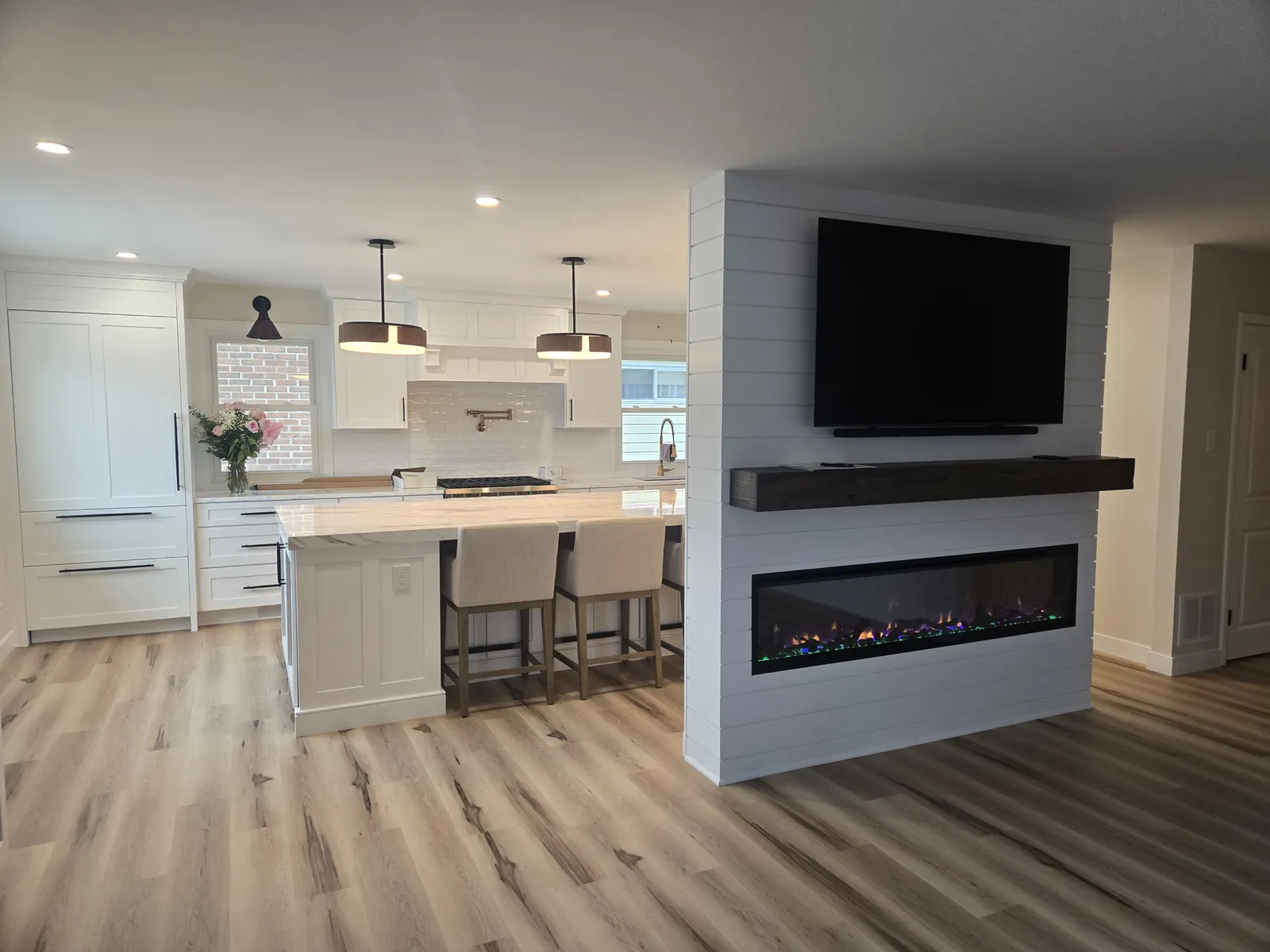 Open kitchen with island facing a shiplap fireplace wall