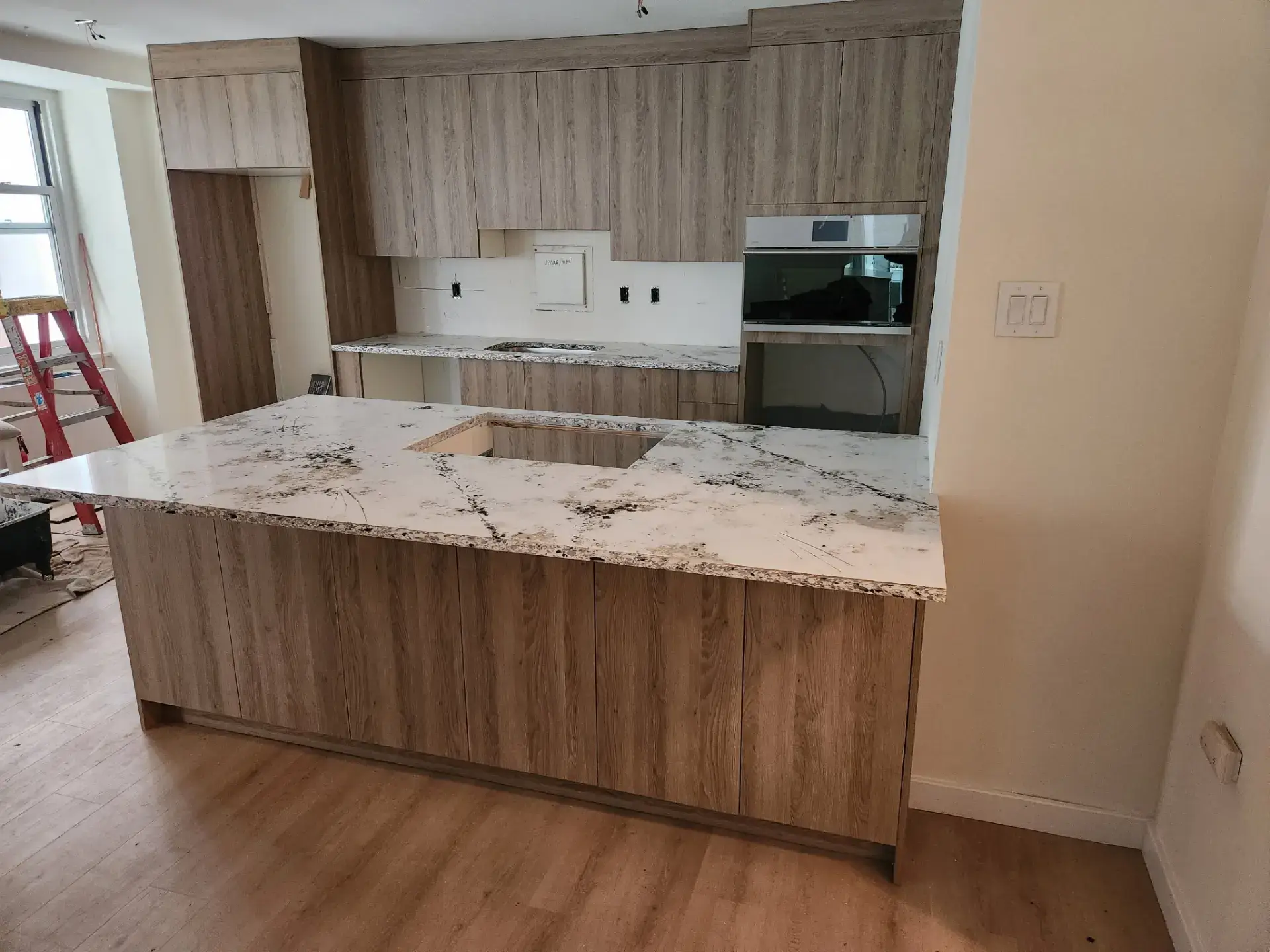 Kitchen cabinetry part way through installation with a step ladder in the room