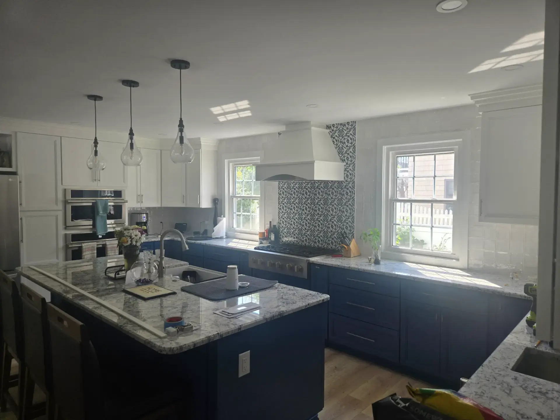 Navy island with a marble countertop and pendant lights