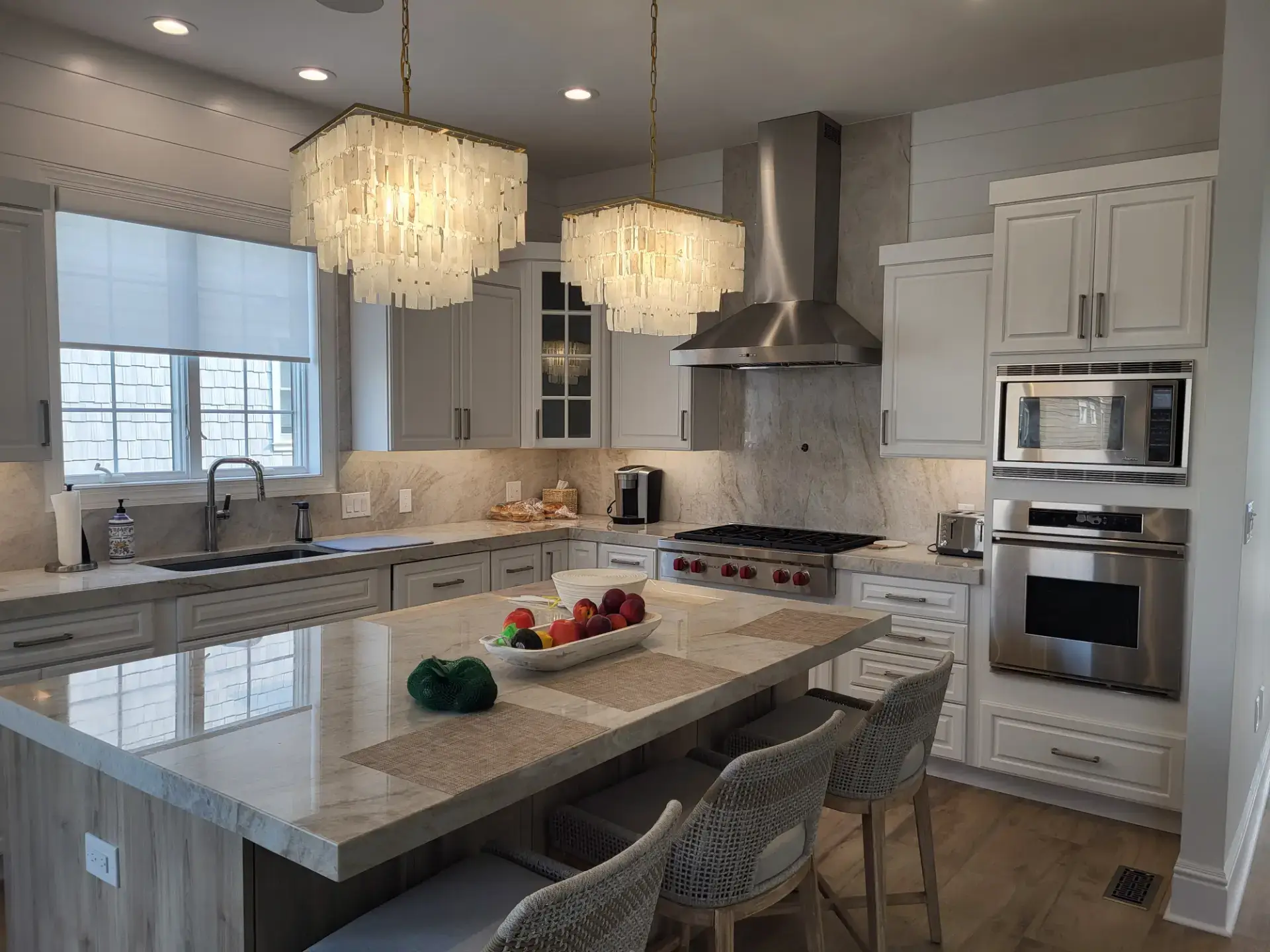 White shaker kitchen with a large island and pendant chandeliers