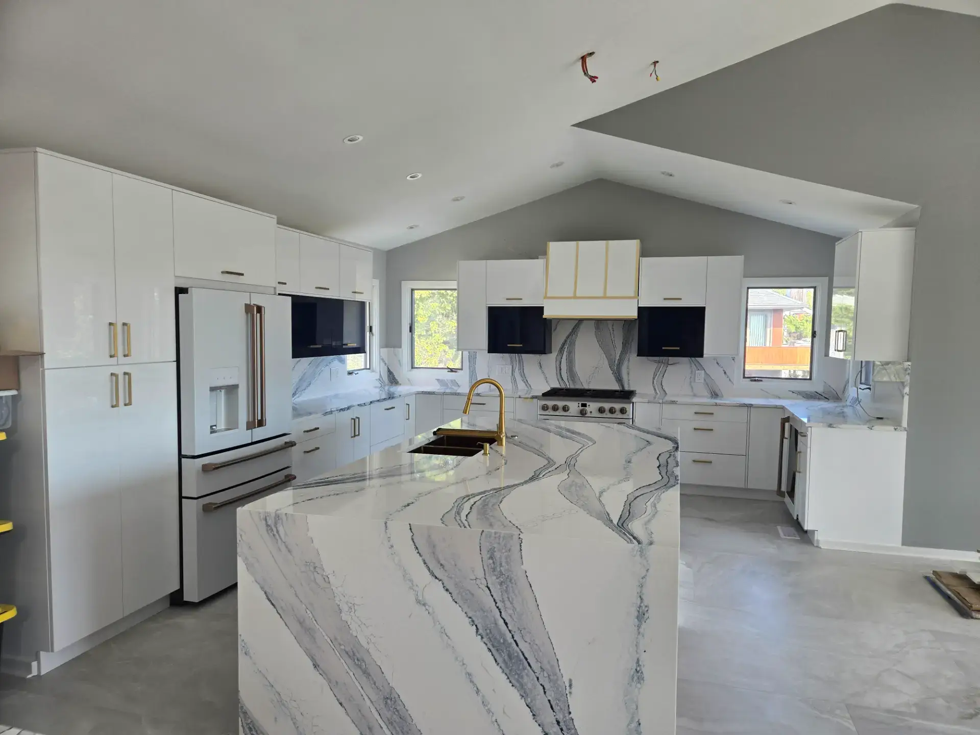 White kitchen under a vaulted ceiling with marble countertops