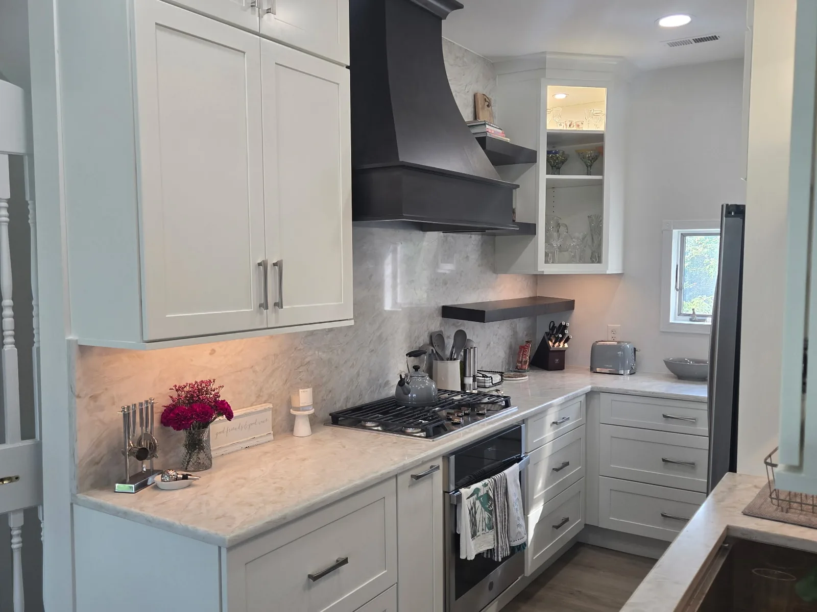White shaker kitchen with a curved dark hood surround and a full height stone backsplash
